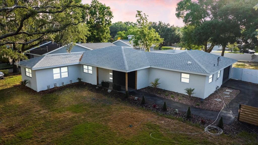 a aerial view of a house next to a big yard with plants and large tree