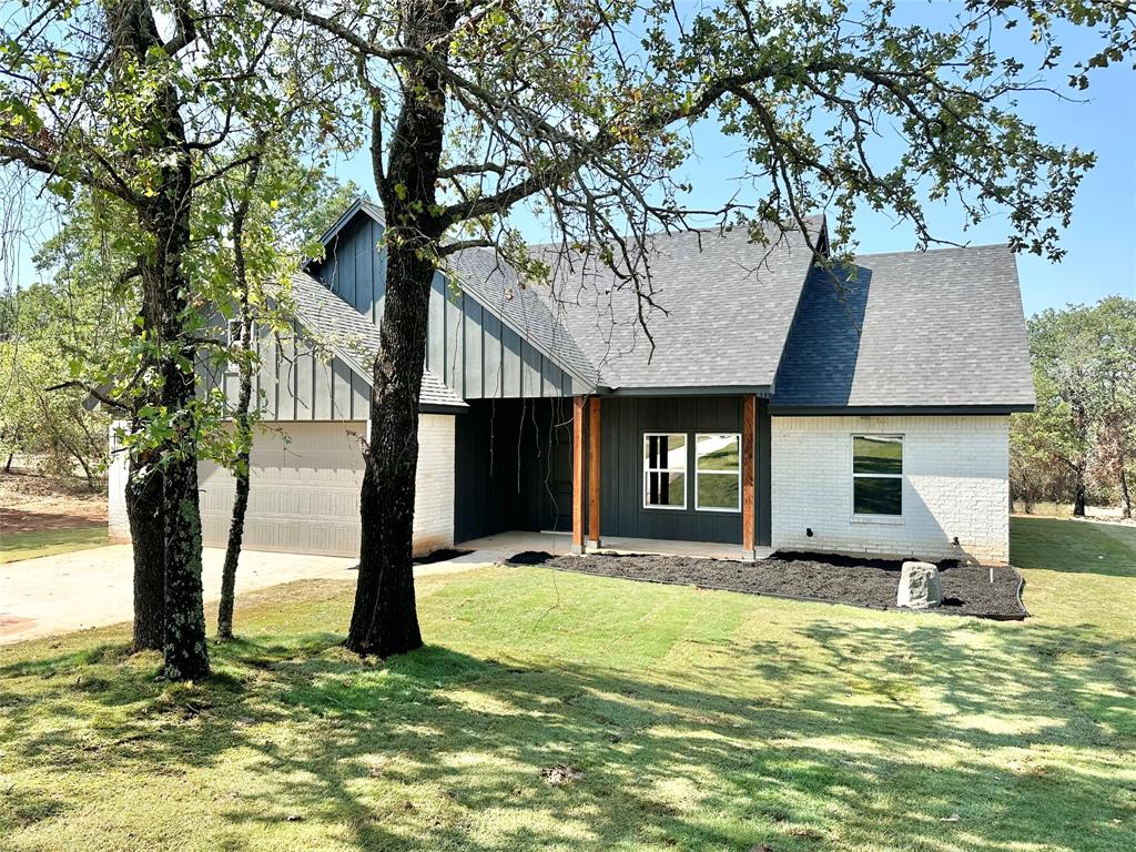 a front view of house with yard and trees in the background