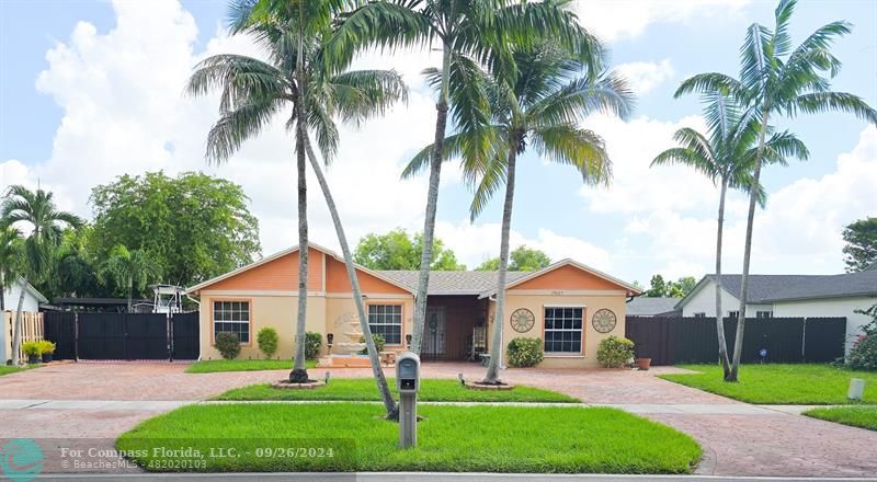 a front view of a house with a garden and palm trees