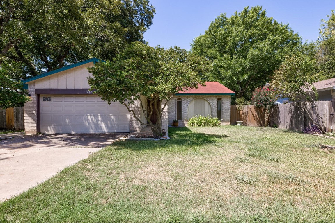 a view of a house with a yard and large tree