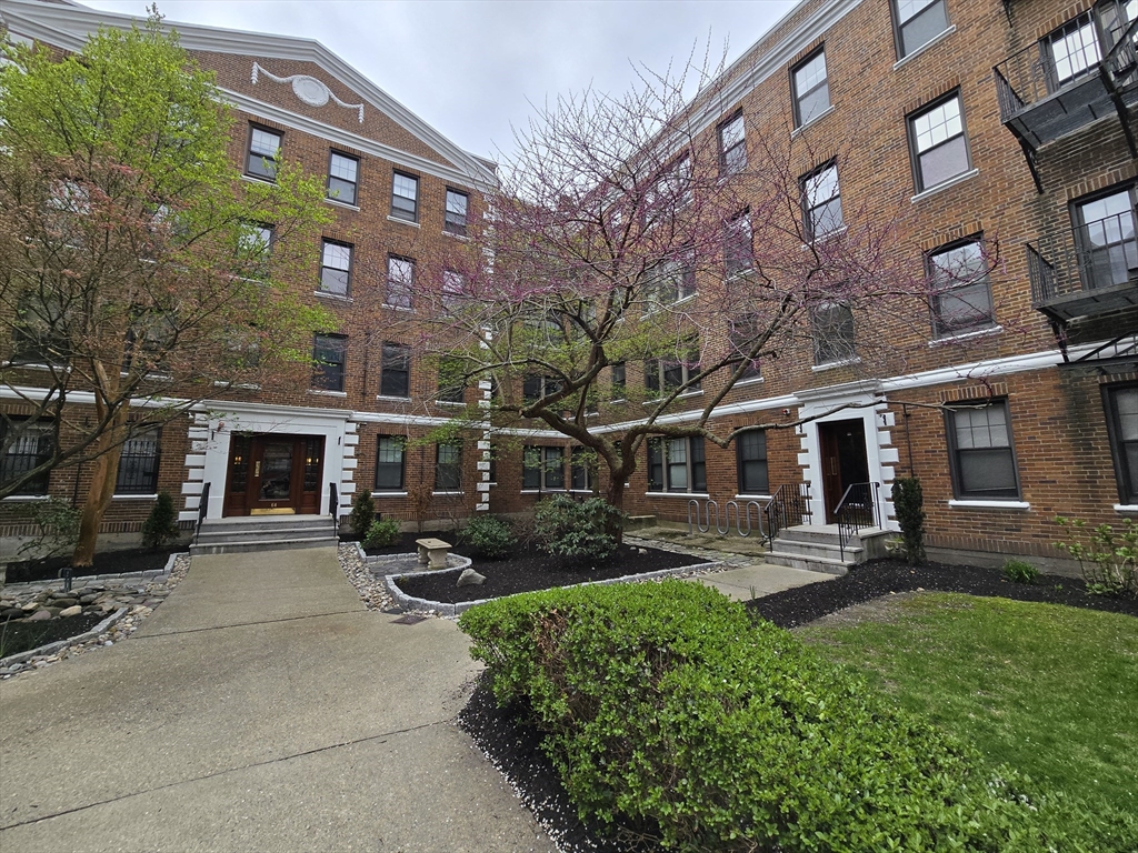 a front view of a building with yard and outdoor seating