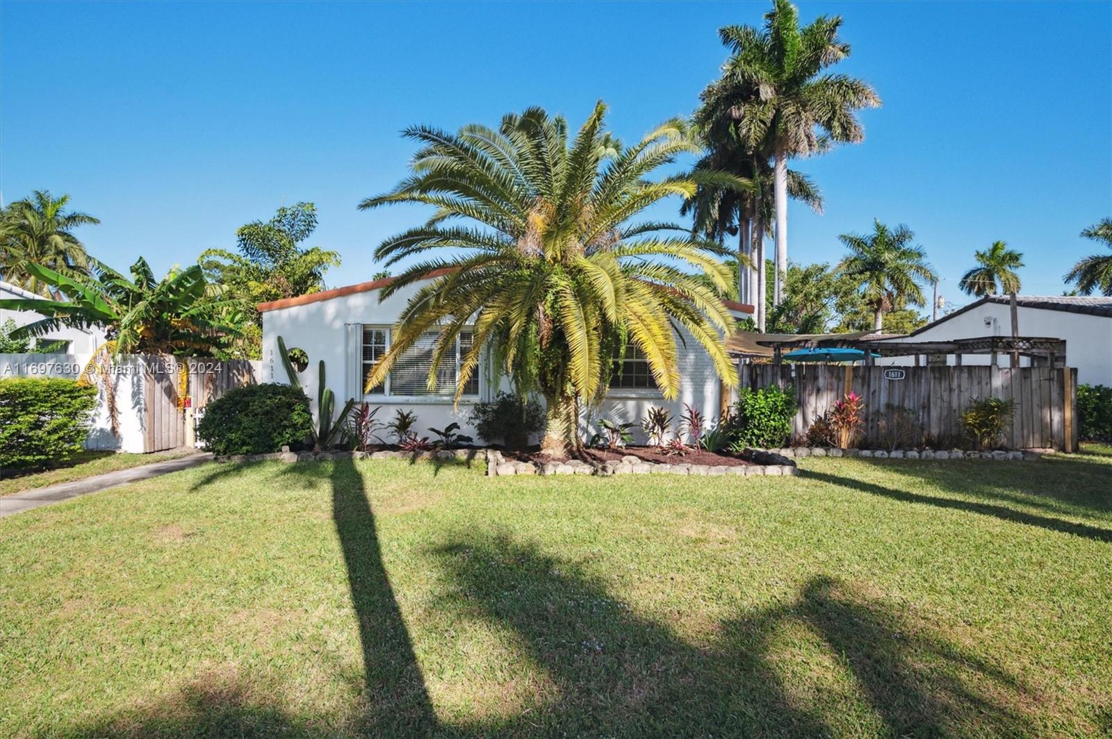 a view of a house with a yard and palm trees