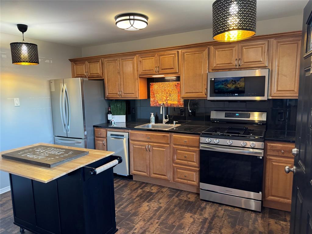 a kitchen with stainless steel appliances granite countertop a stove a sink and a microwave