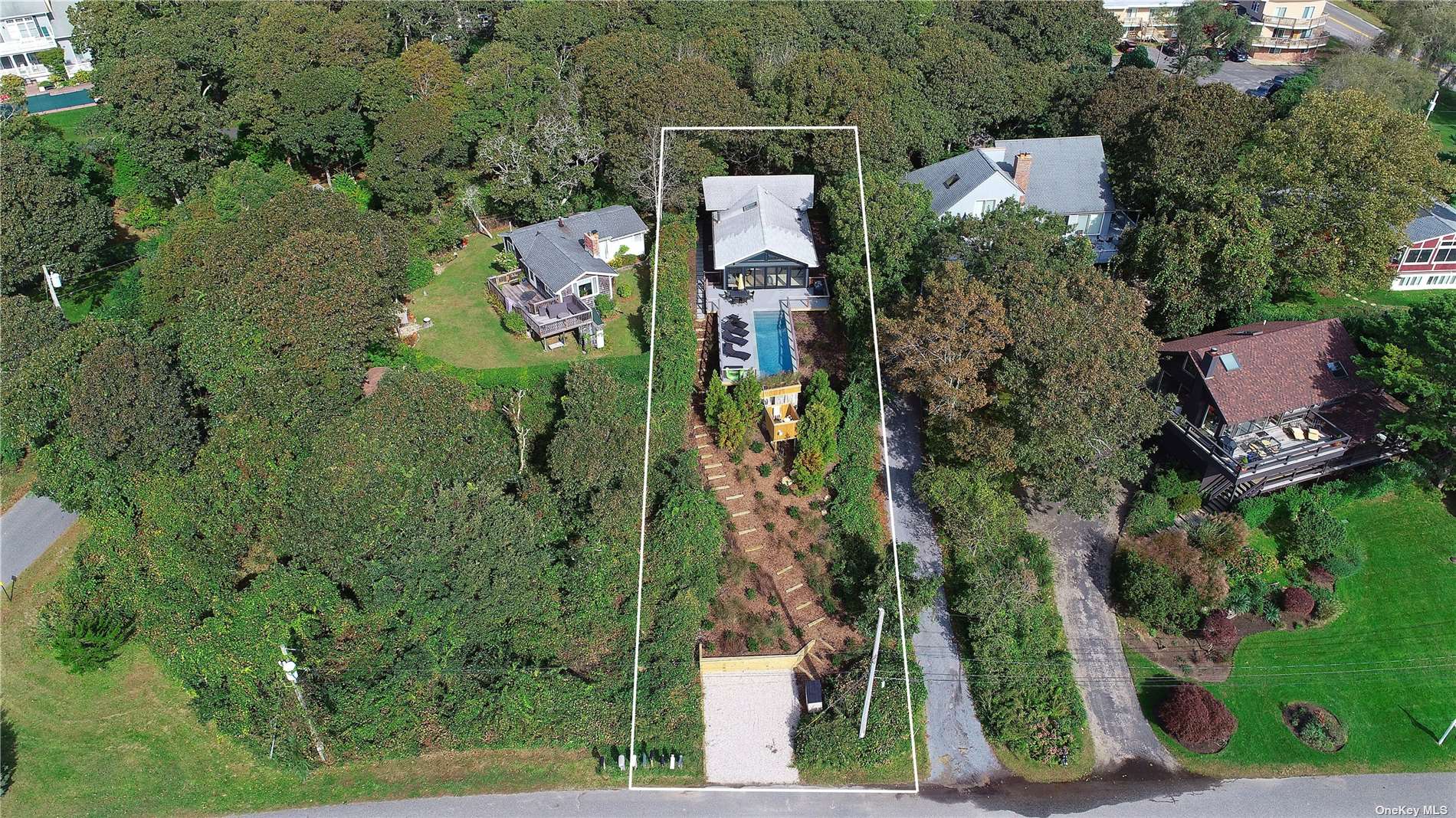 an aerial view of residential house with outdoor space and trees all around