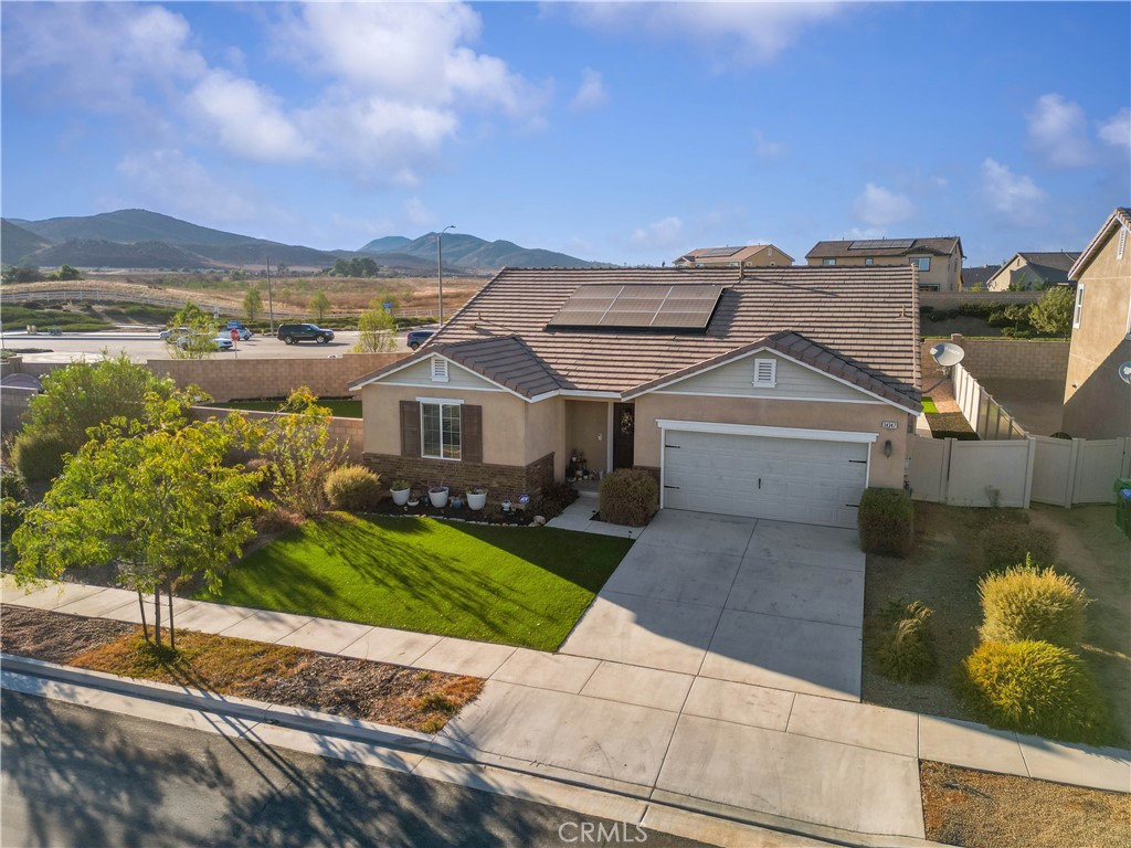 a front view of a house with a yard and mountain view in back