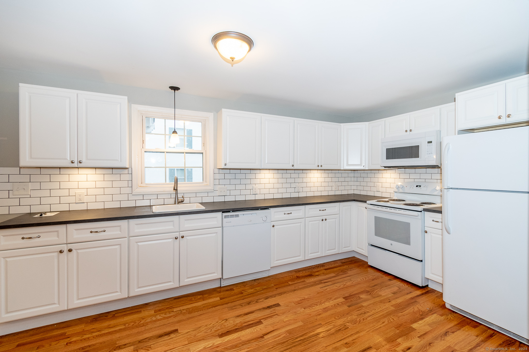 a kitchen with granite countertop white cabinets and white appliances