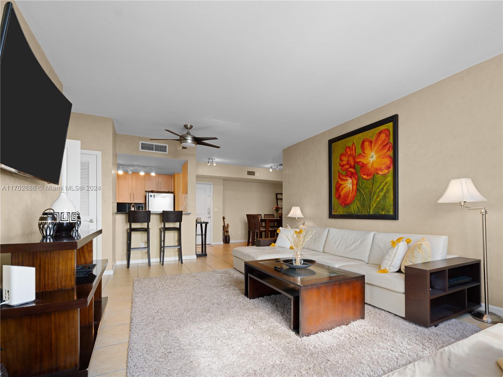 a living room with furniture a flat screen tv and kitchen view