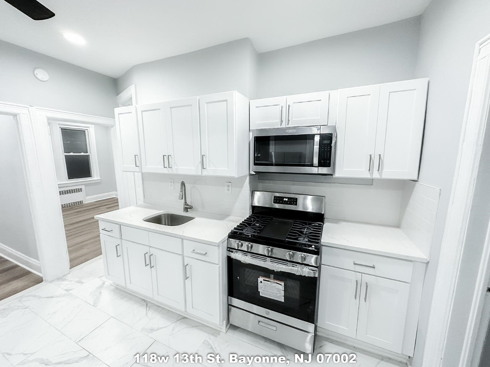 a kitchen with white cabinets stainless steel appliances and sink