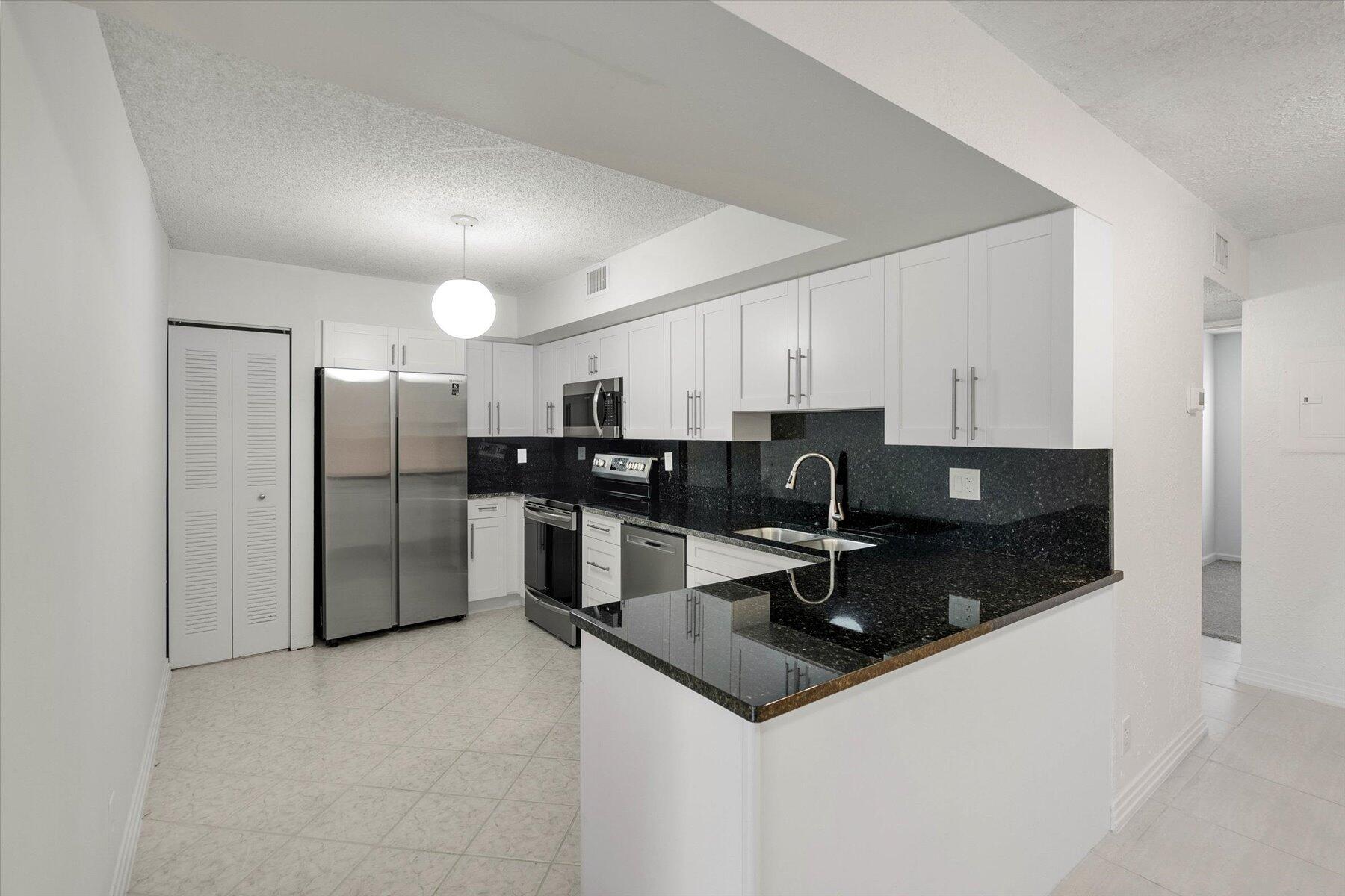 a kitchen with stainless steel appliances granite countertop a sink a stove and refrigerator