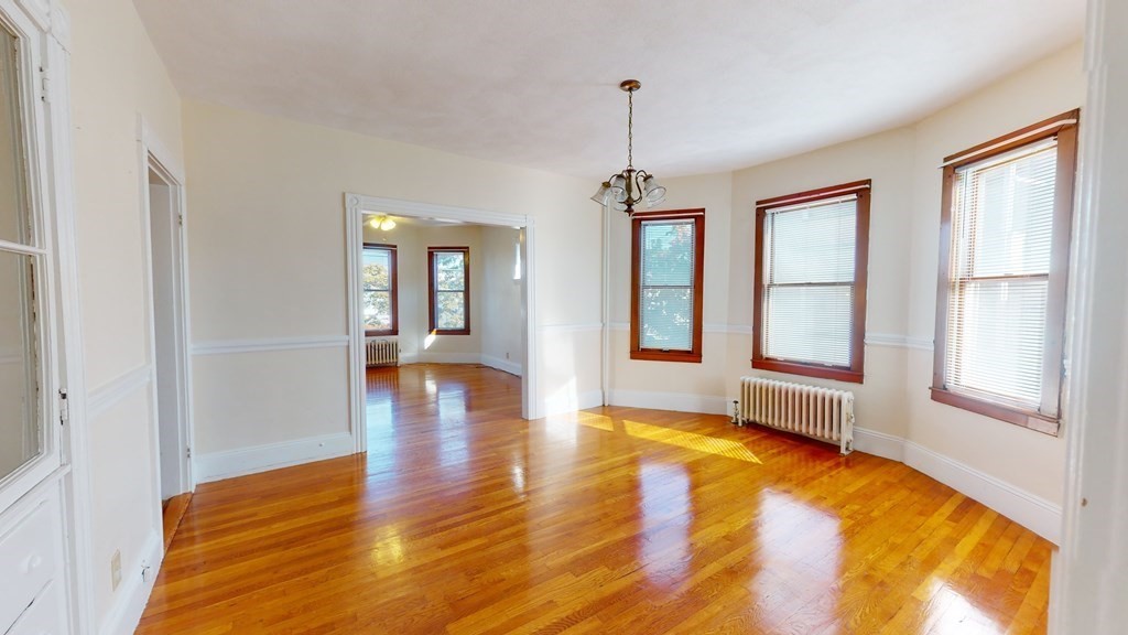 a view of an empty room with window and wooden floor