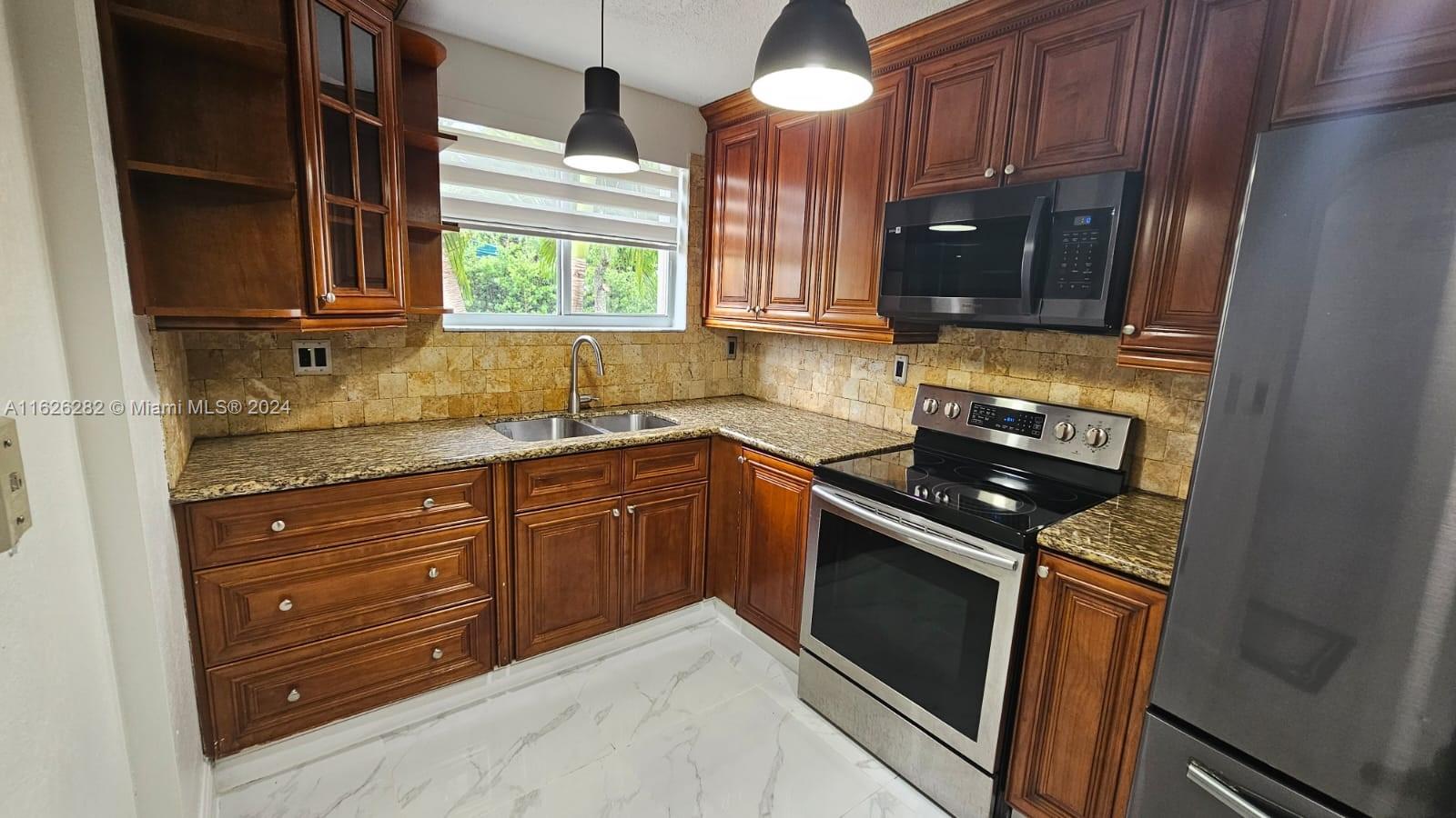 a kitchen with granite countertop stainless steel appliances stove microwave and sink