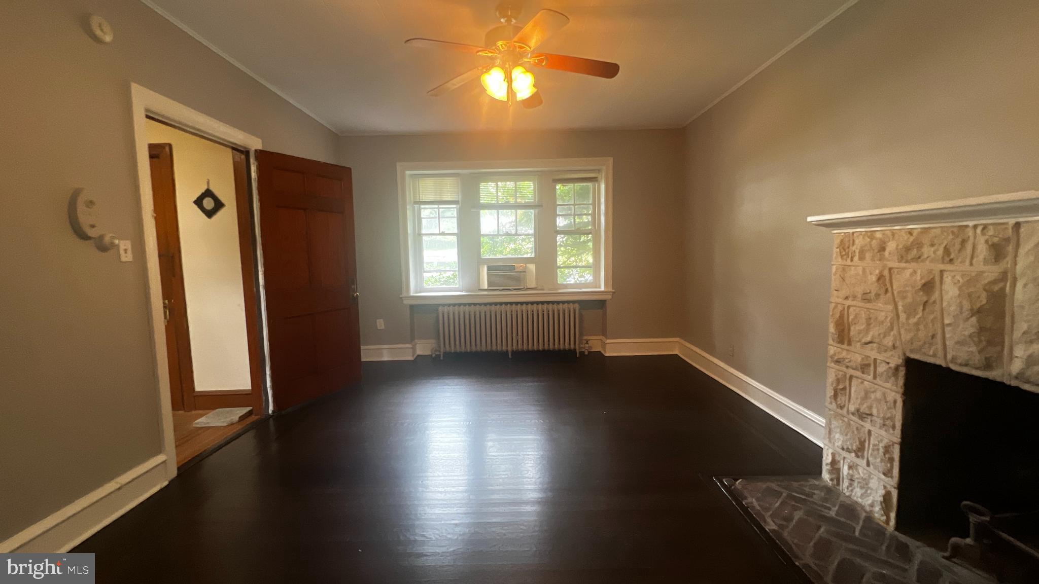 an empty room with wooden floor fireplace and windows