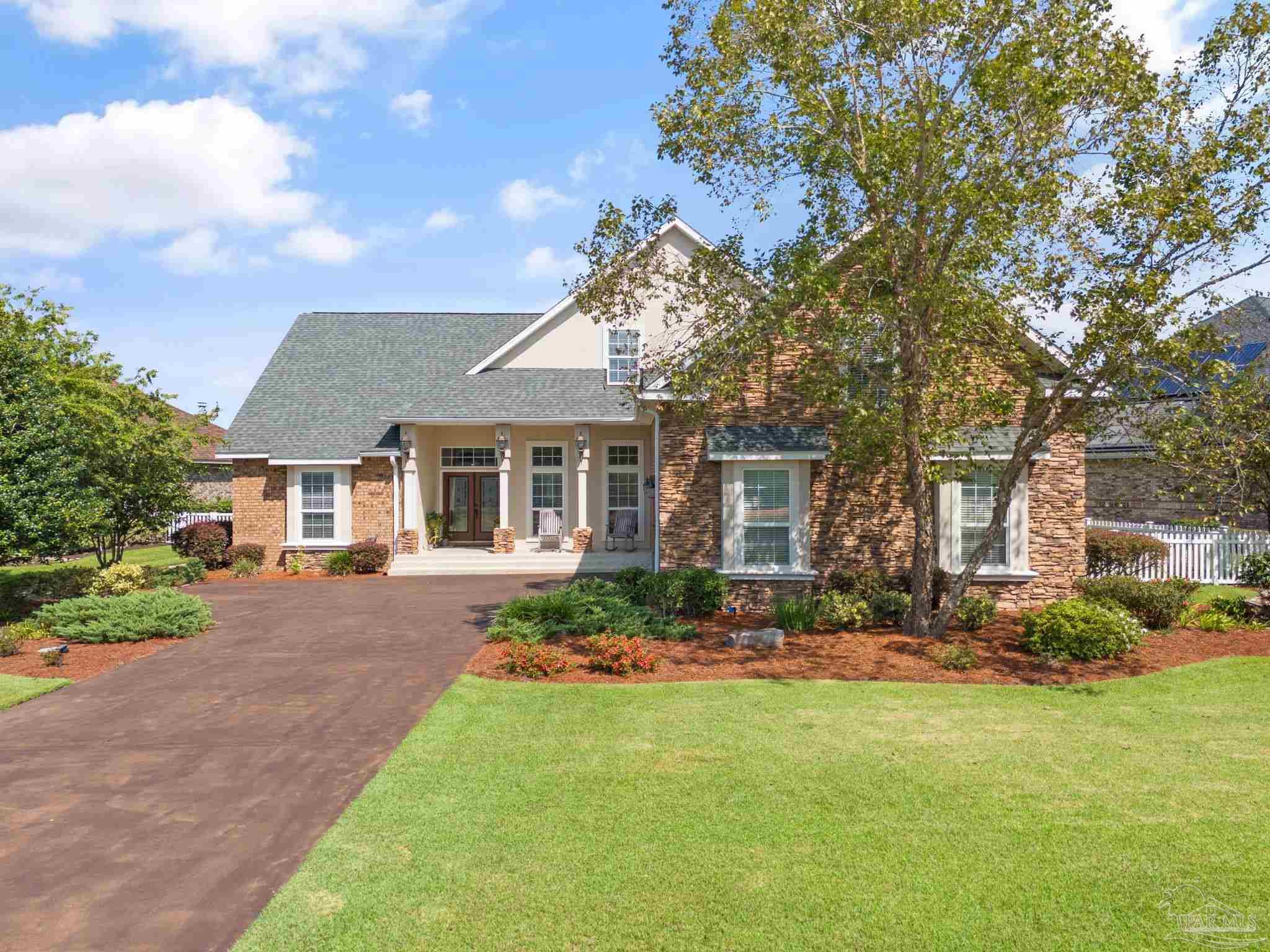 a front view of a house with a garden and trees