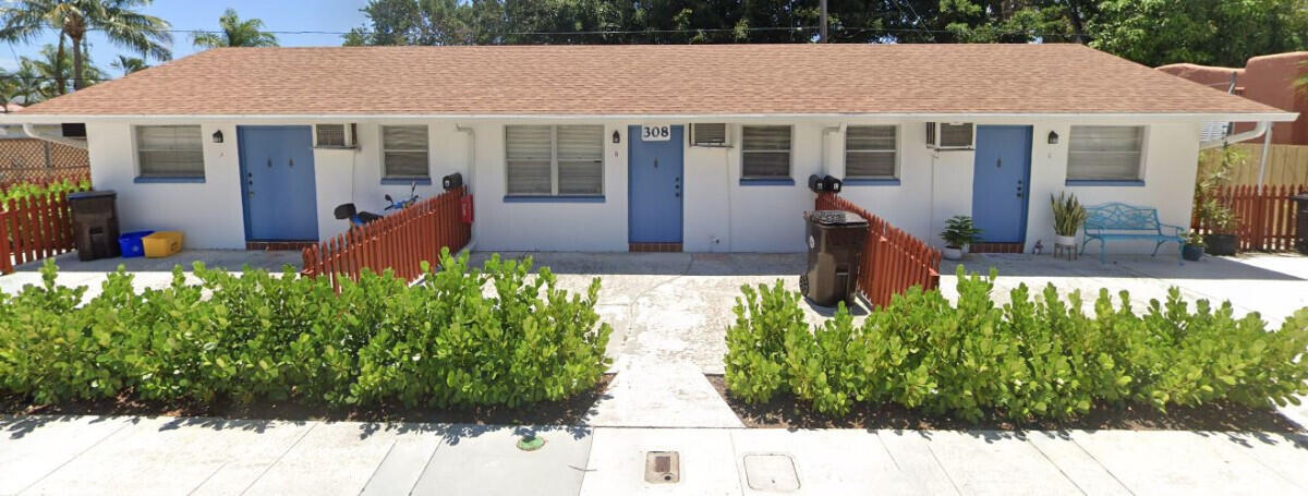 a view of a house with potted plants and a yard in front of it