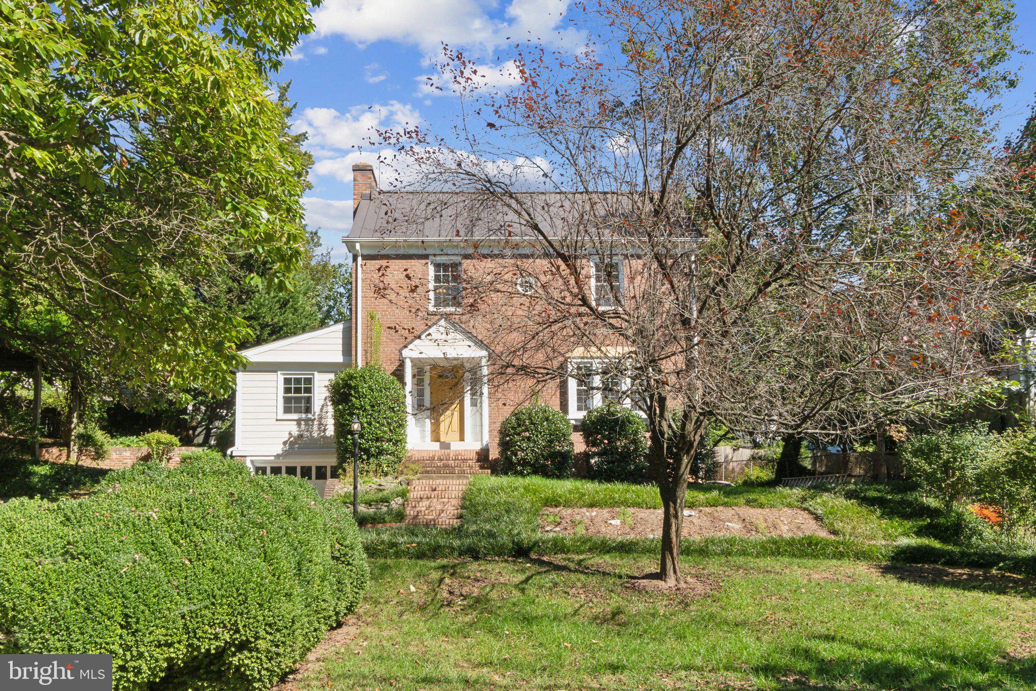 a view of a white house next to a yard with big trees