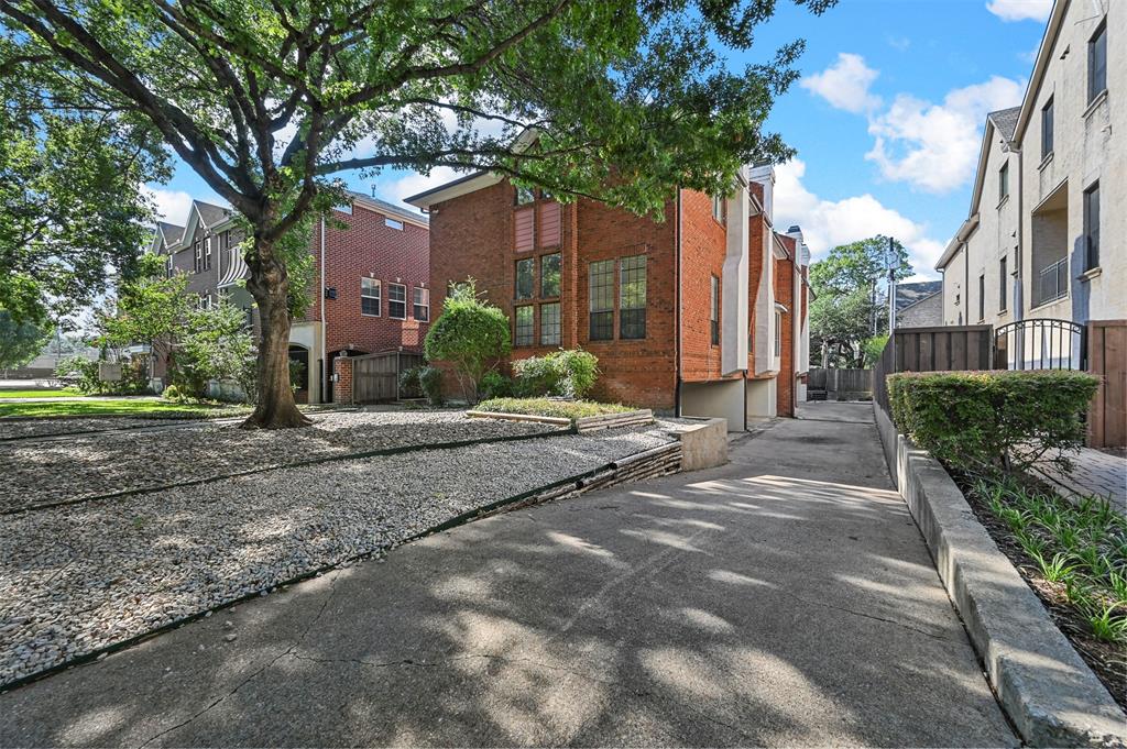 a view of a house with brick walls plants and large tree