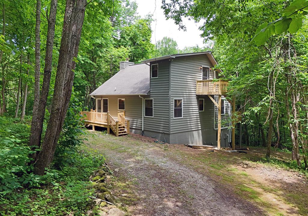 a view of a house with a yard and large trees