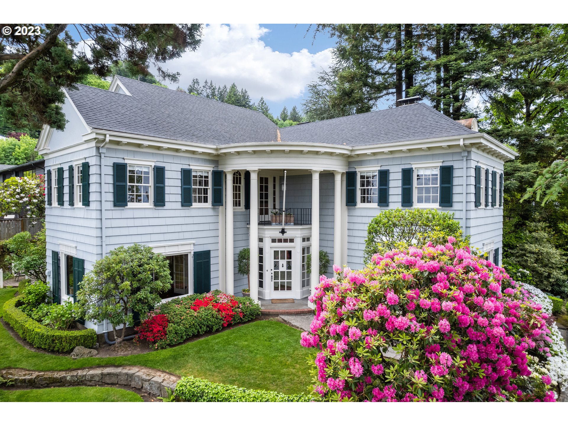 a front view of a house with a big yard and potted plants