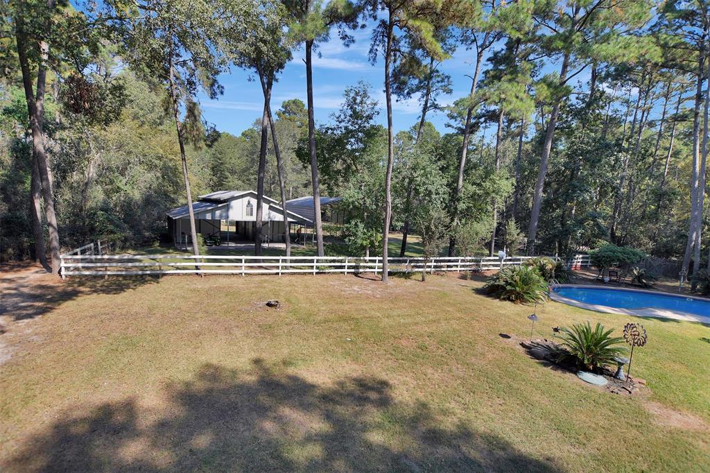 a view of swimming pool with lawn chairs and large trees