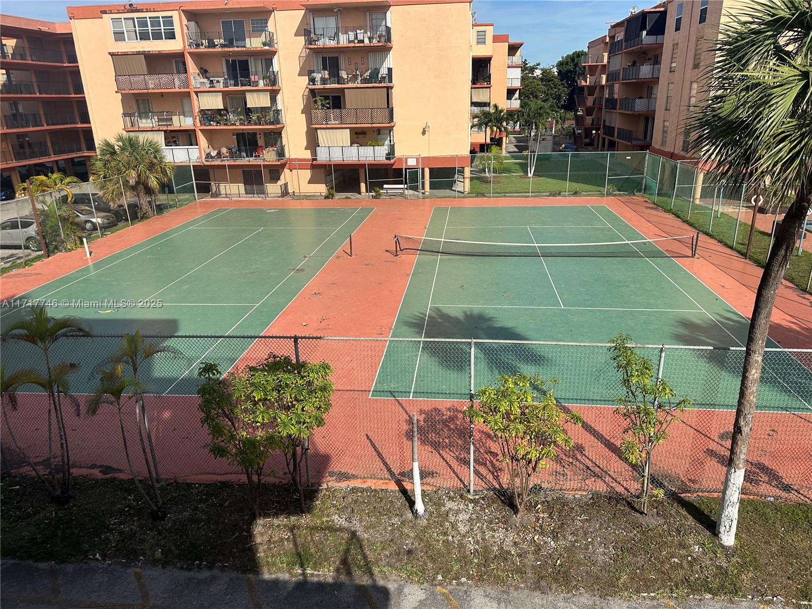 a view of a tennis ground with a lawn chairs under an umbrella