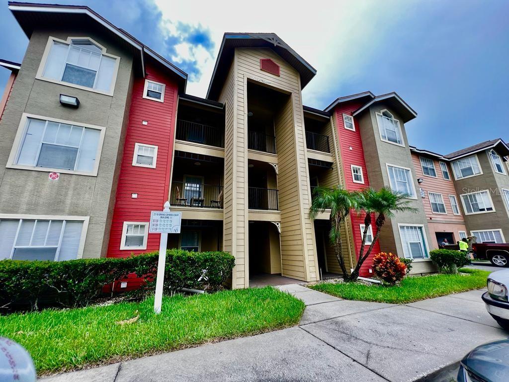 a front view of a multi story residential apartment building with yard and green space