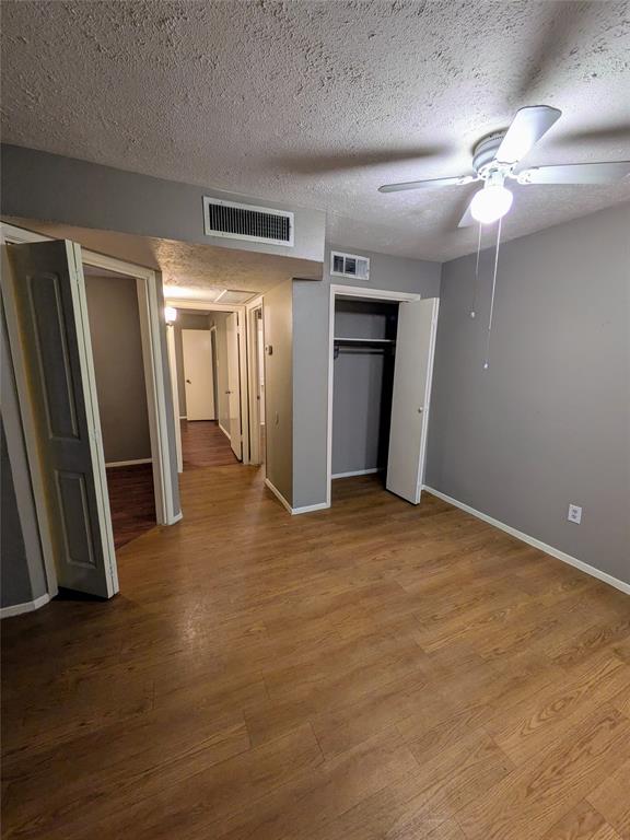 an empty room with wooden floor and a ceiling fan