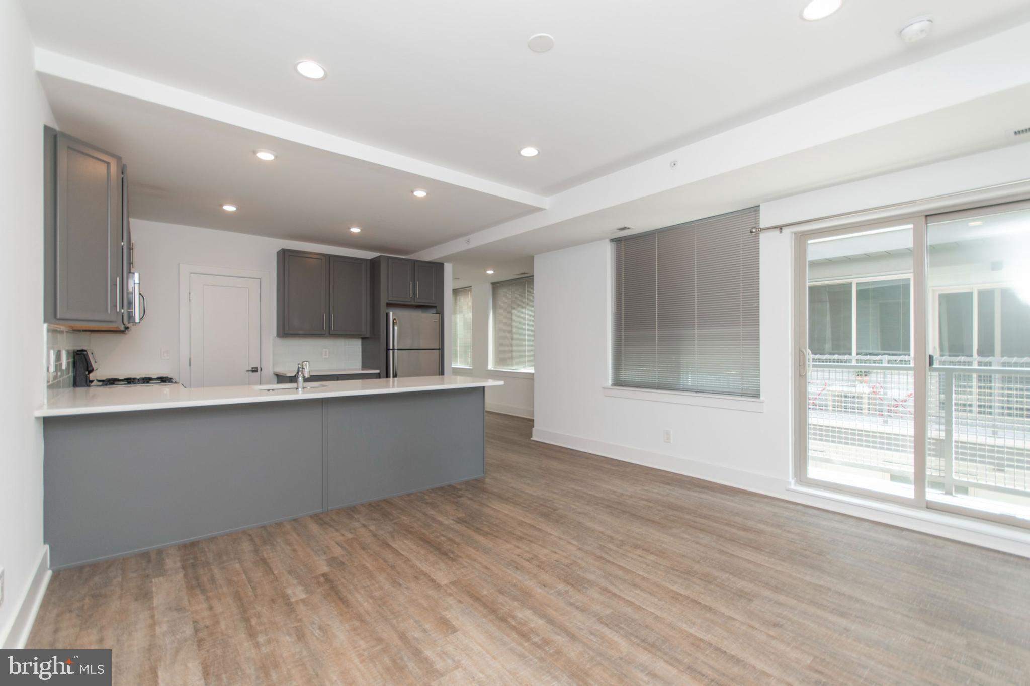 a large kitchen with stainless steel appliances a large counter top and a wooden floor