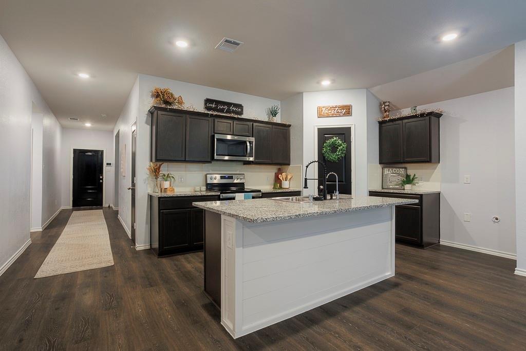 a large kitchen with stainless steel appliances a large counter top a stove and a sink