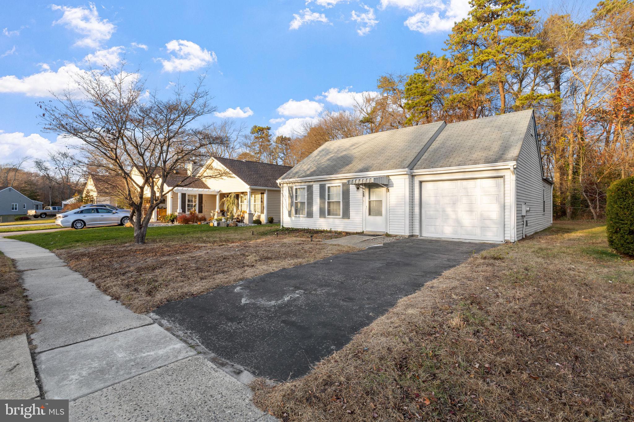 a view of a white house next to a yard with big trees