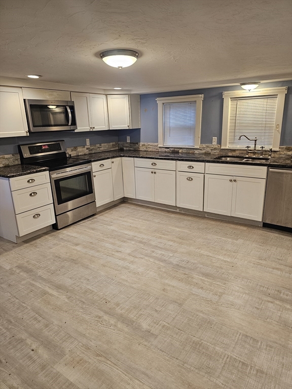 a large kitchen with granite countertop a stove top oven a sink and dishwasher