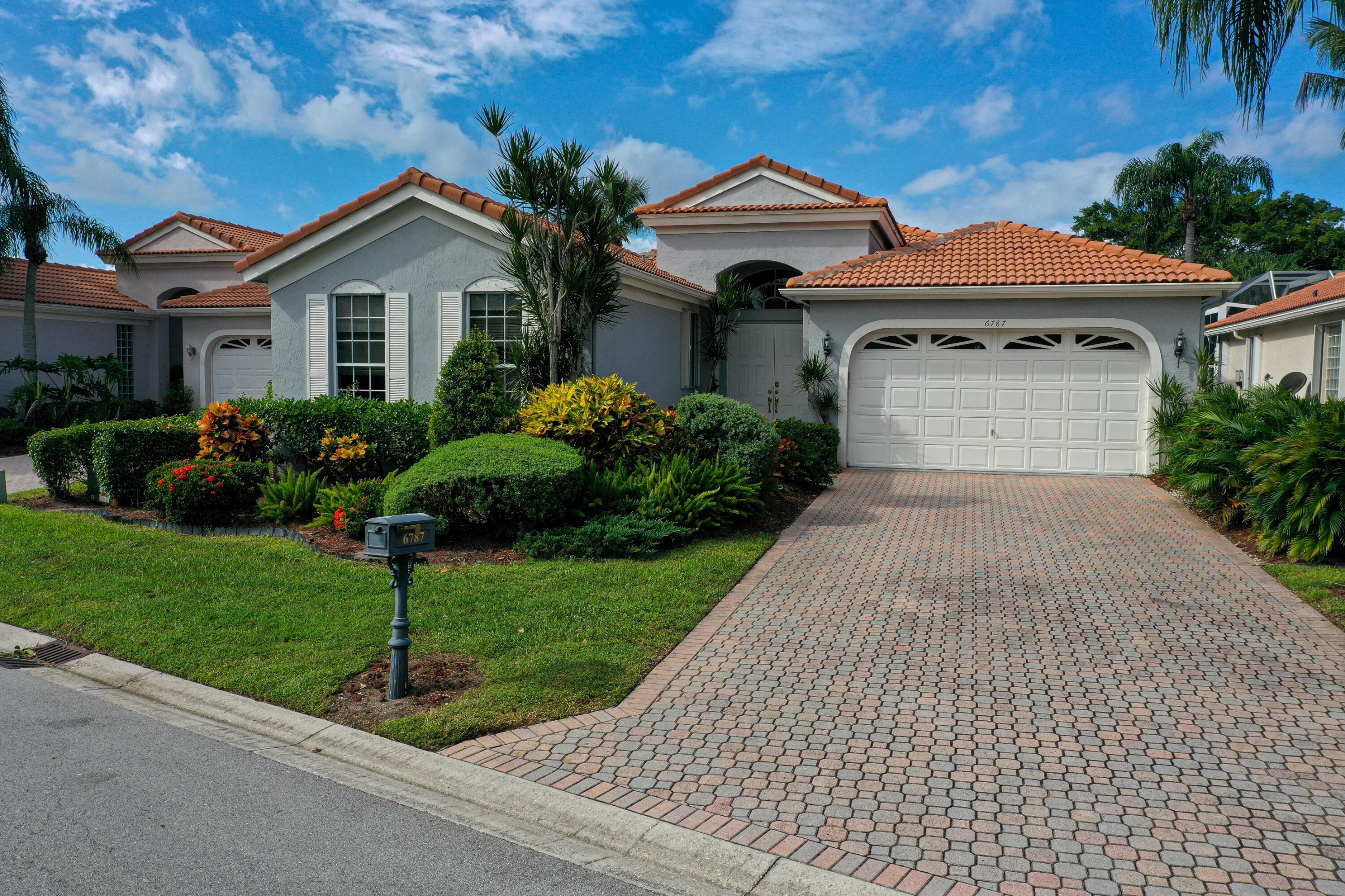 a front view of a house with a yard and potted plants