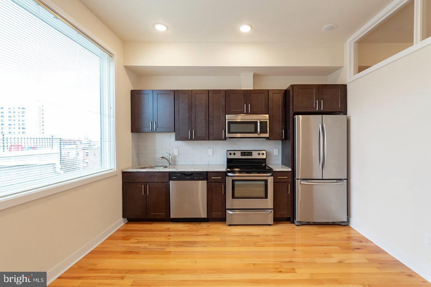 a kitchen with granite countertop a refrigerator stove top oven and sink