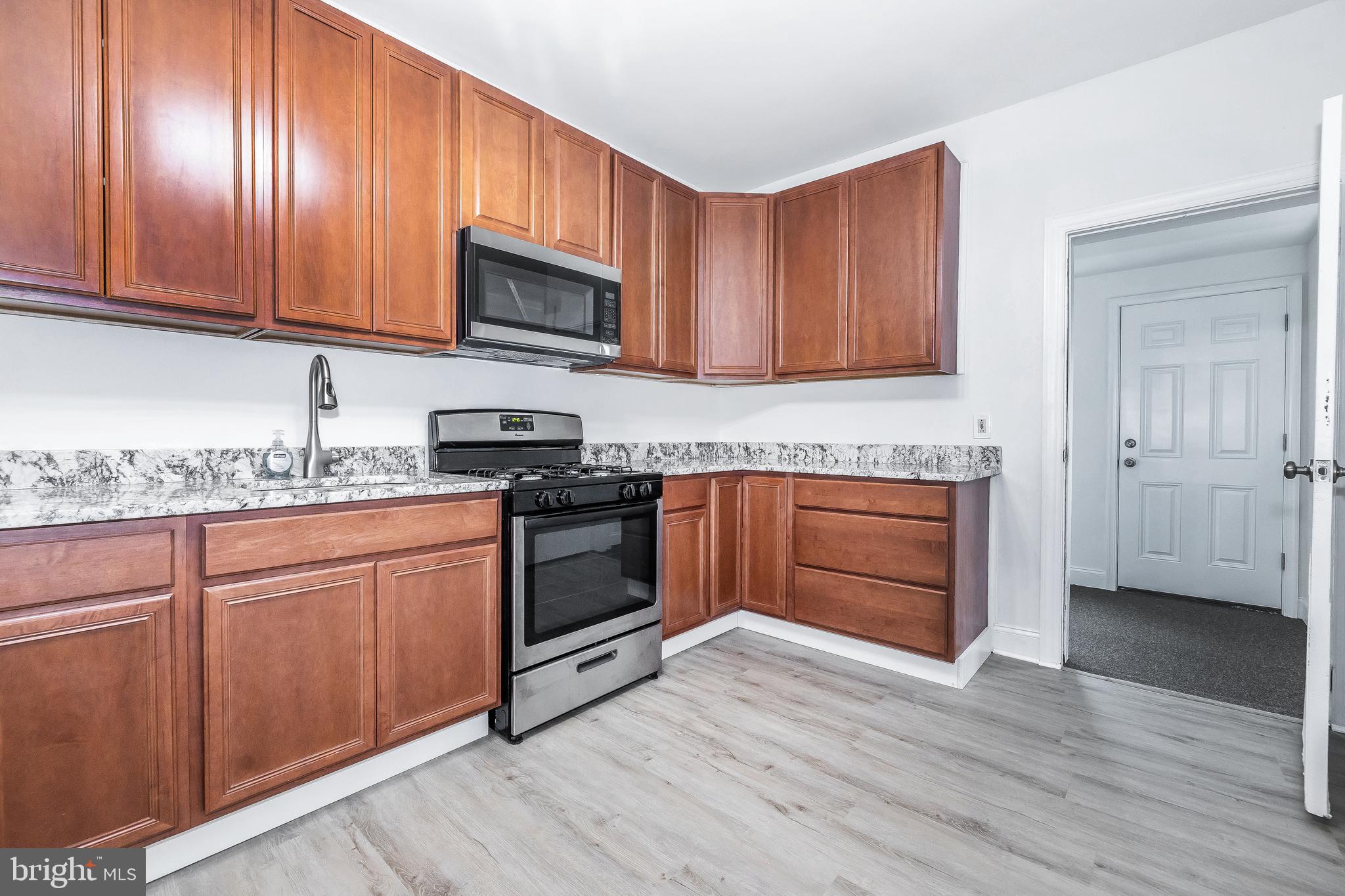 a kitchen with granite countertop wooden cabinets and white appliances