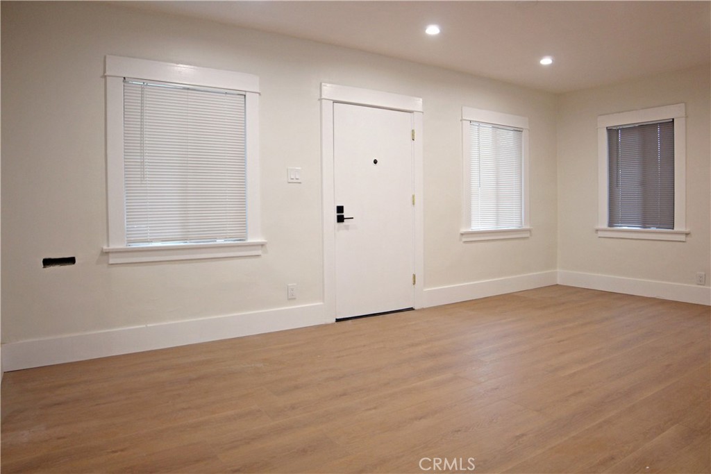 a view of an empty room with wooden floor and window