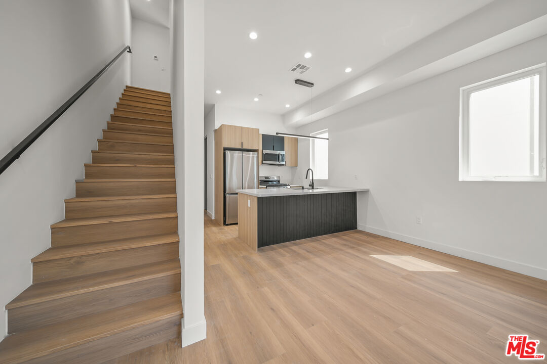 a view of kitchen and empty room with wooden floor