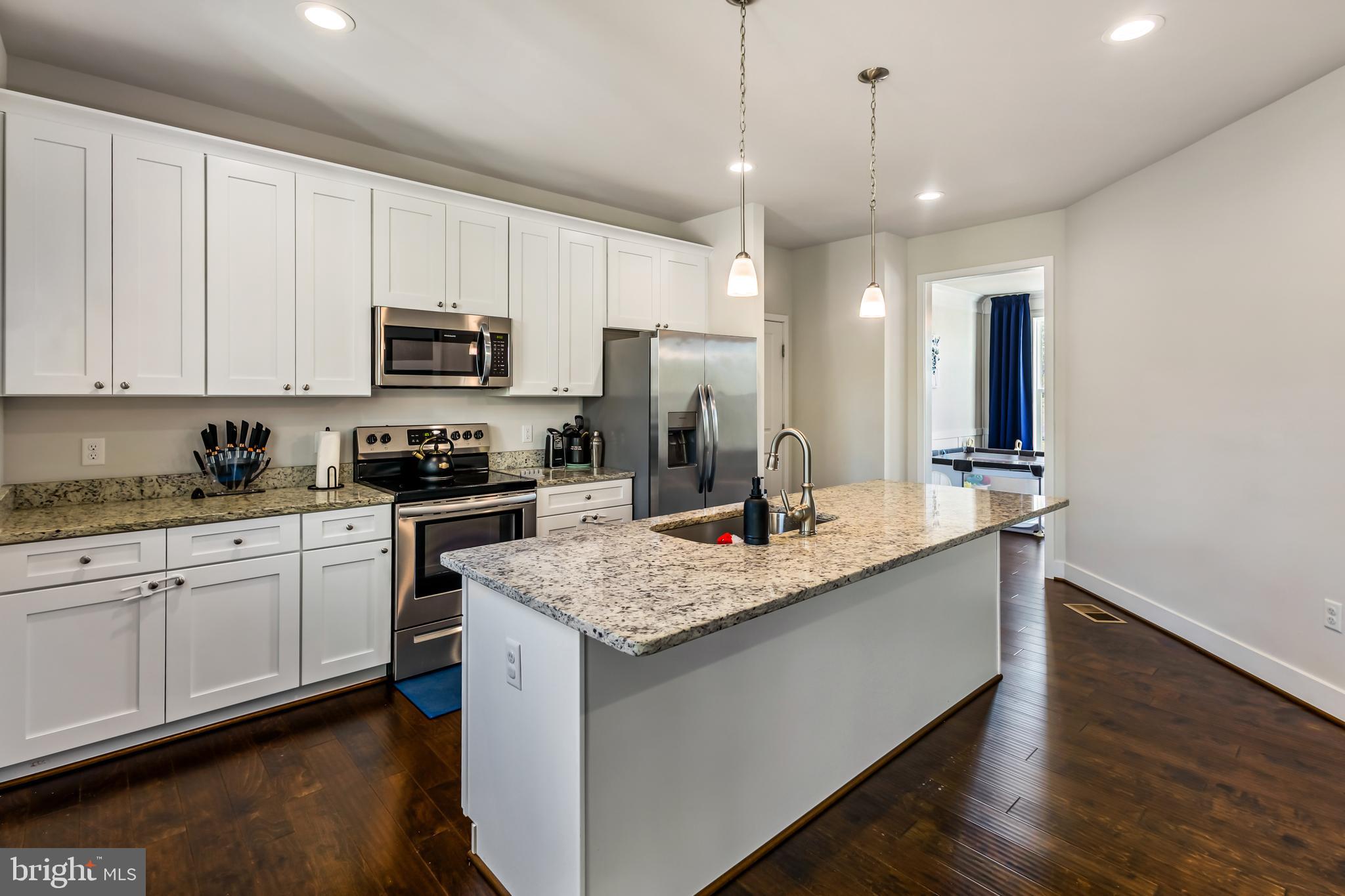 a kitchen with kitchen island granite countertop a sink a counter top space appliances and cabinets