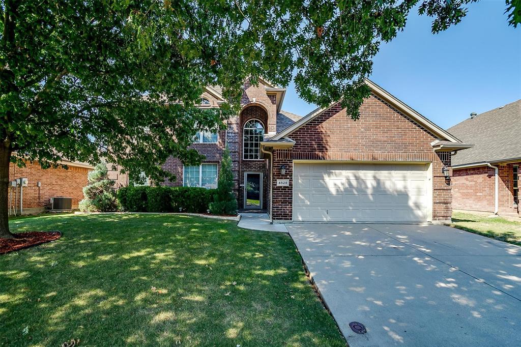 View of property featuring central AC unit, a garage, and a front lawn