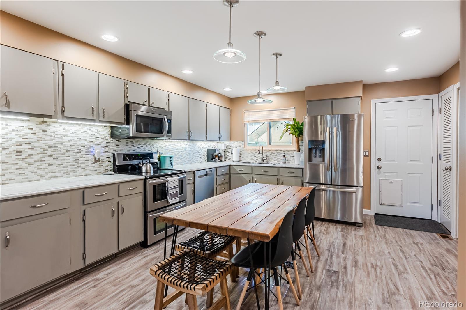 a kitchen with stainless steel appliances a dining table chairs microwave and refrigerator