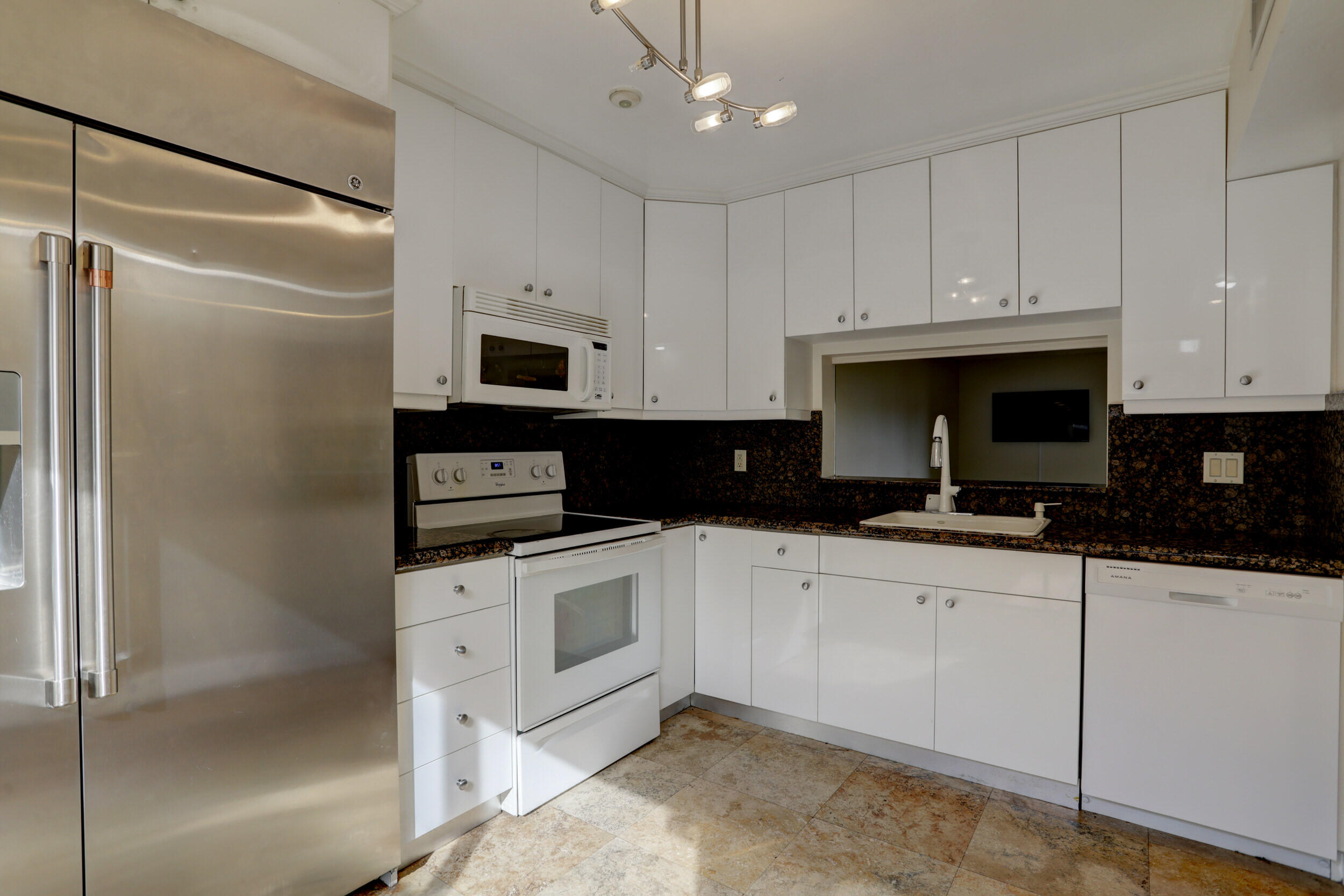 a kitchen with granite countertop white cabinets and stainless steel appliances