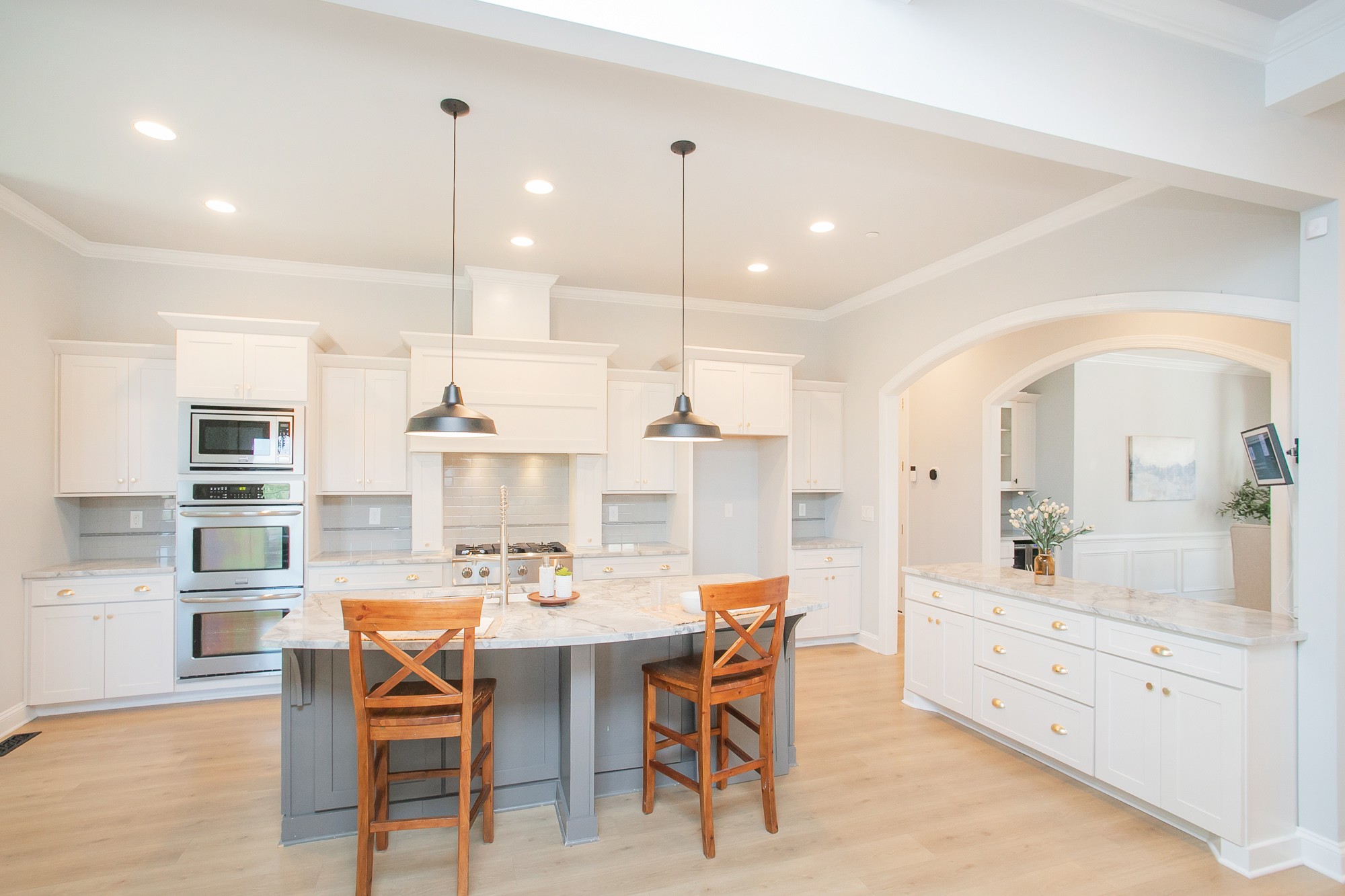 a kitchen with stainless steel appliances kitchen island granite countertop a dining table chairs and white cabinets