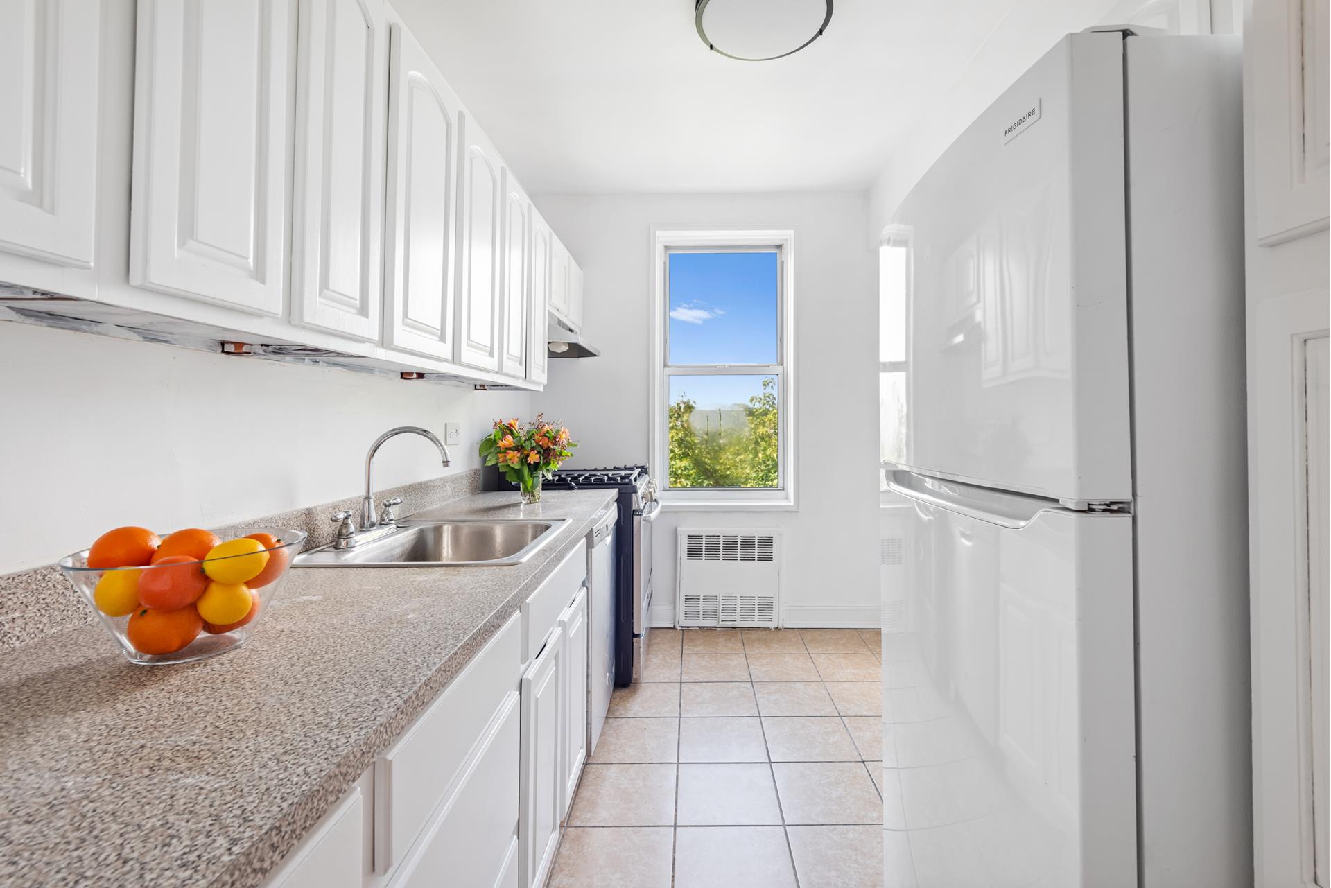 a kitchen with stainless steel appliances granite countertop a sink a refrigerator and a white cabinets