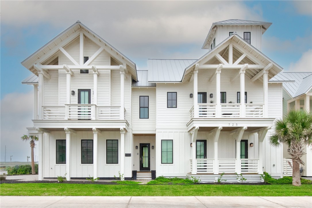 a view of a white house with large windows and a small yard