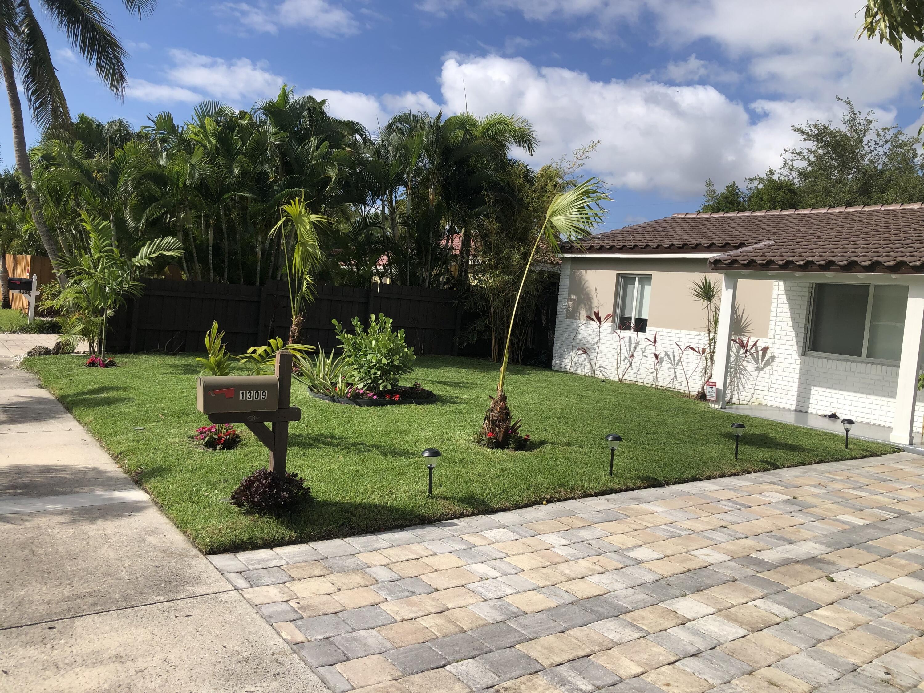 a view of a white house with a yard and potted plants