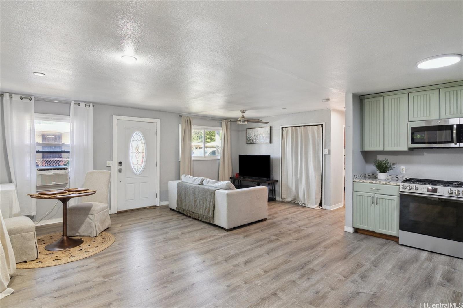 a living room with furniture a flat screen tv and kitchen view