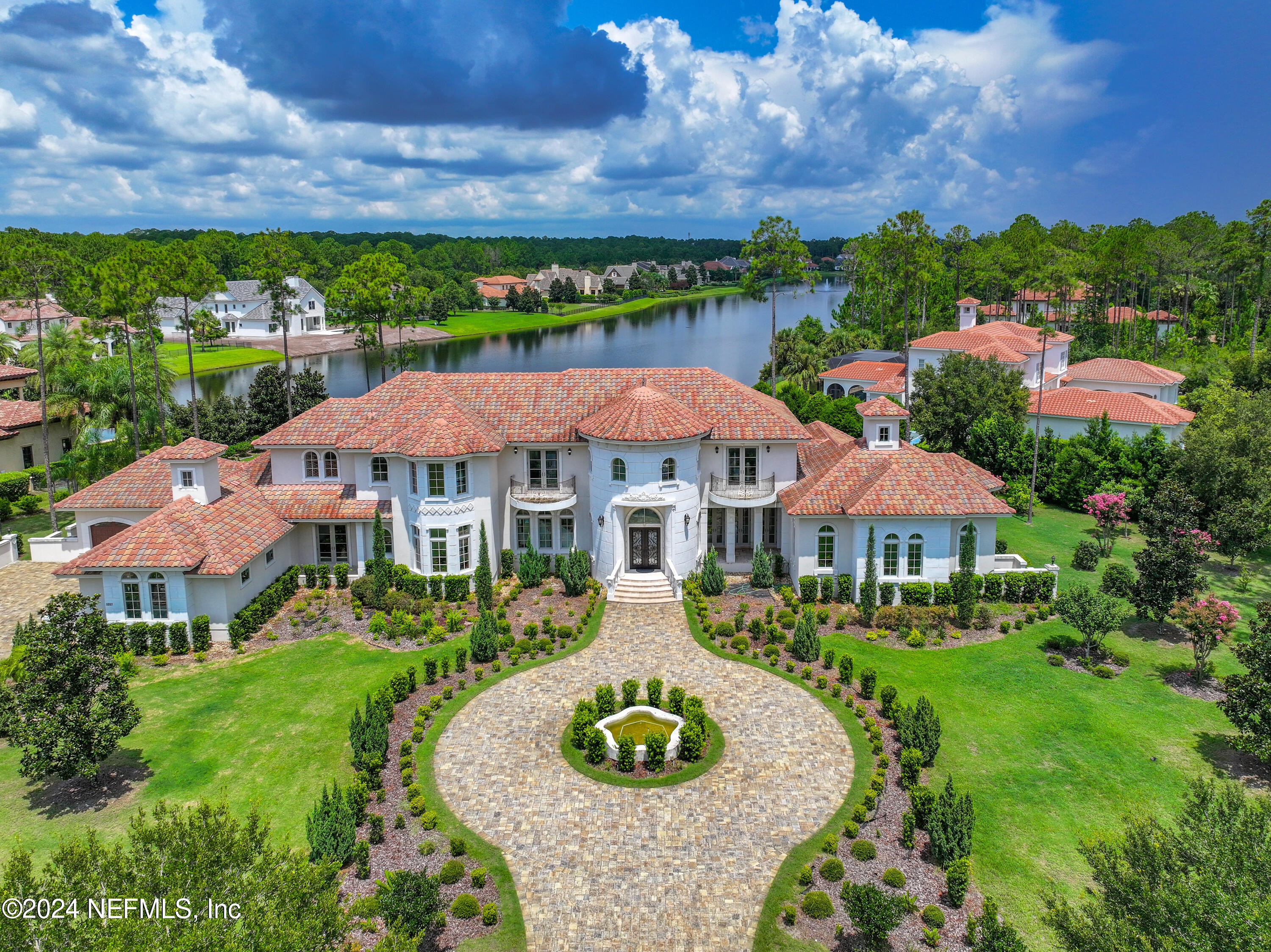 a view of a white house with a big yard plants and large trees