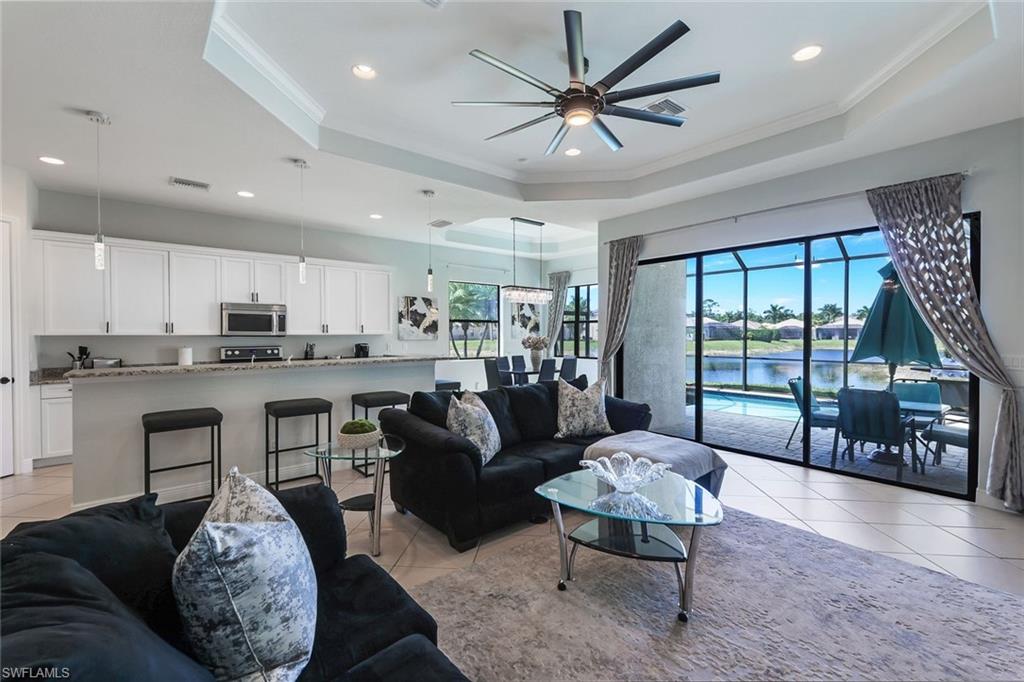 Tiled living room with ceiling fan, crown molding, and a tray ceiling