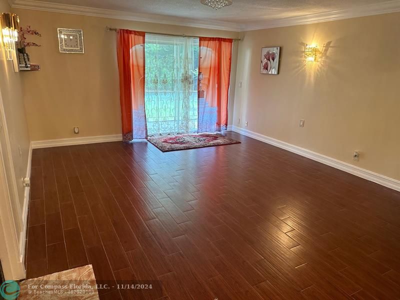 an empty room with wooden floor and windows with curtains