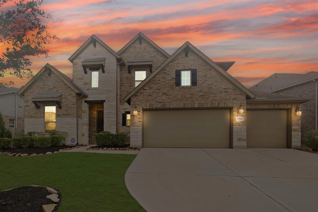 Welcome to 13514 Noble Landing! This is a spacious two-story brick home featuring a large driveway and an attached three-car garage, set against a beautiful sunset sky. The property boasts well-maintained landscaping and a welcoming entrance.