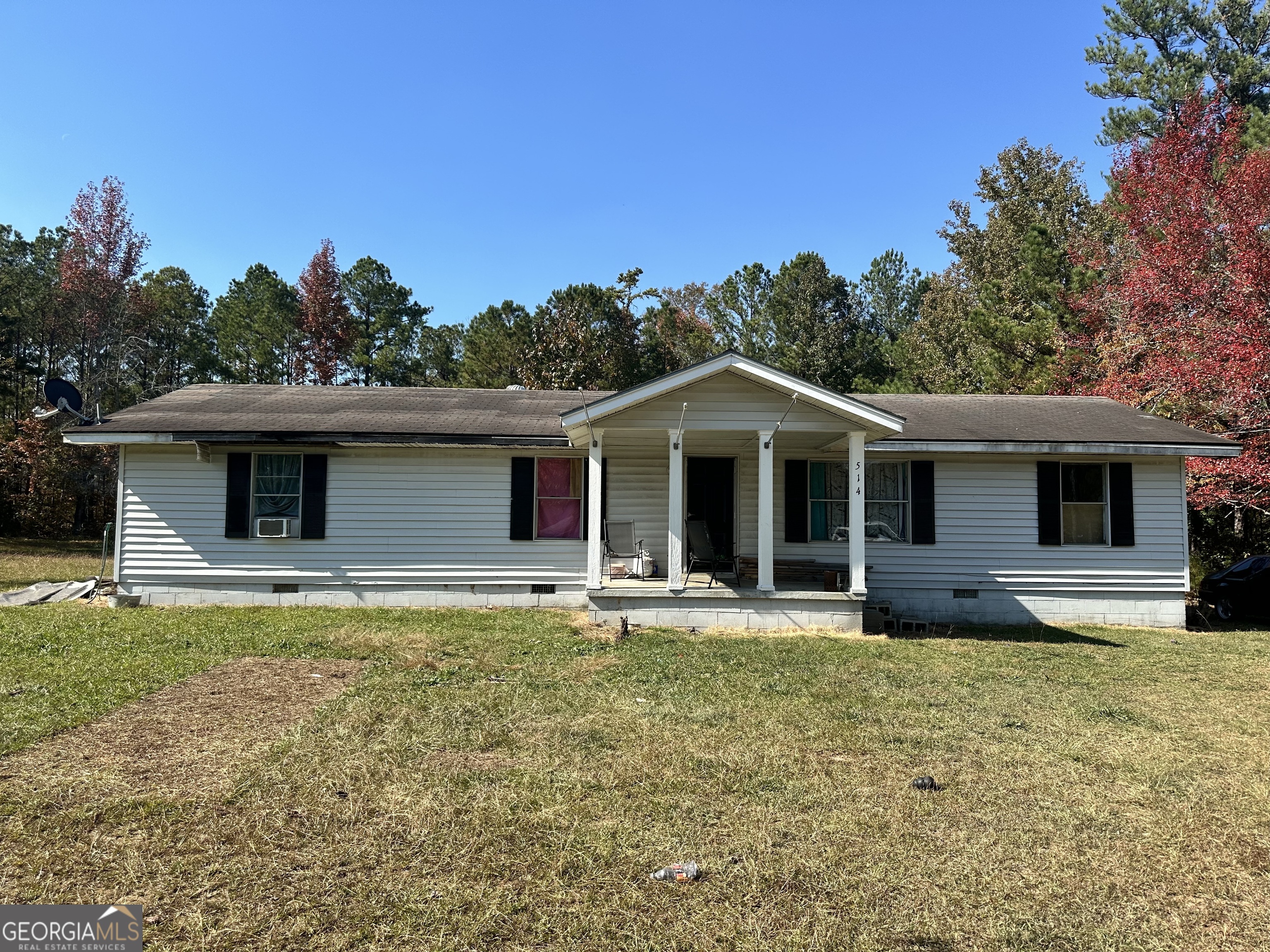 a front view of house with yard and trees in the background