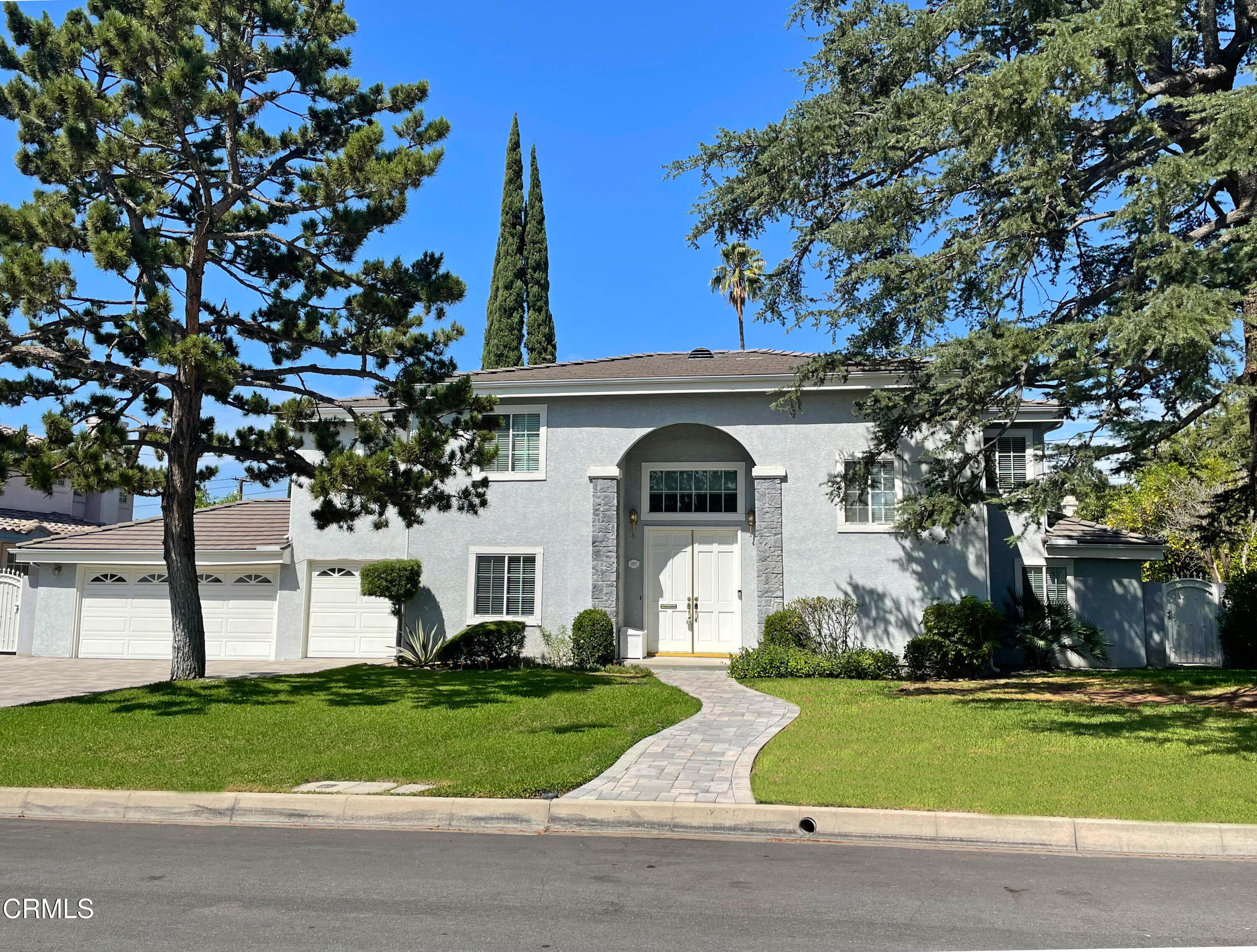 a white house with a yard and a large tree